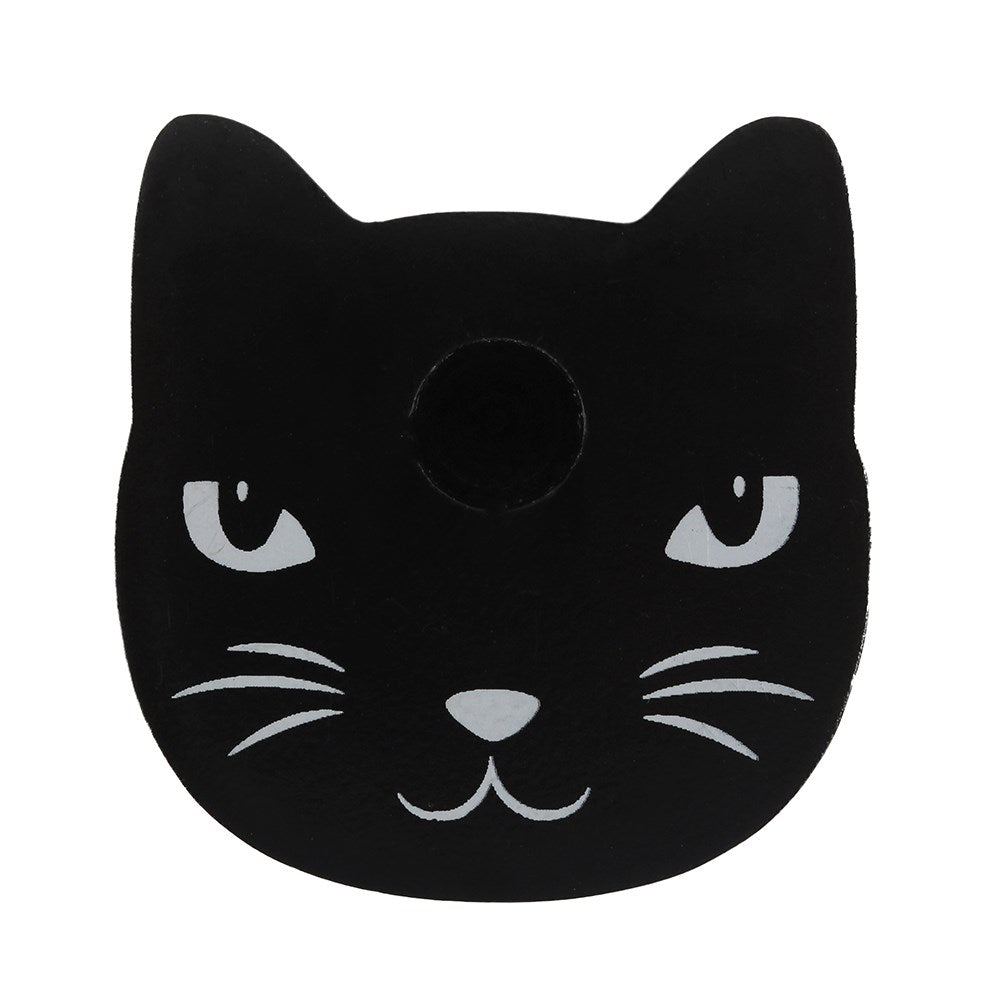 A direct front-on product cutout shot showcasing the flat black cat-shaped mini ritual candle holder. The adorable design features painted minimalist white eyes, a small triangular nose, a curved mouth, and sleek whiskers, presented sharply against a solid white background.