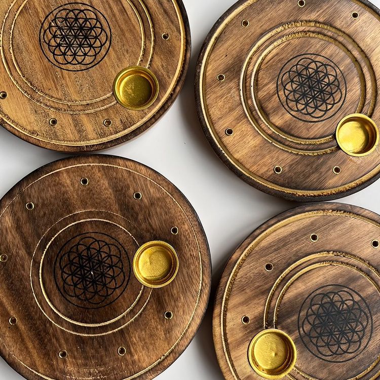 A top-down view of four round mango wood incense holders featuring an engraved sacred geometry design and a small brass cup for cones.