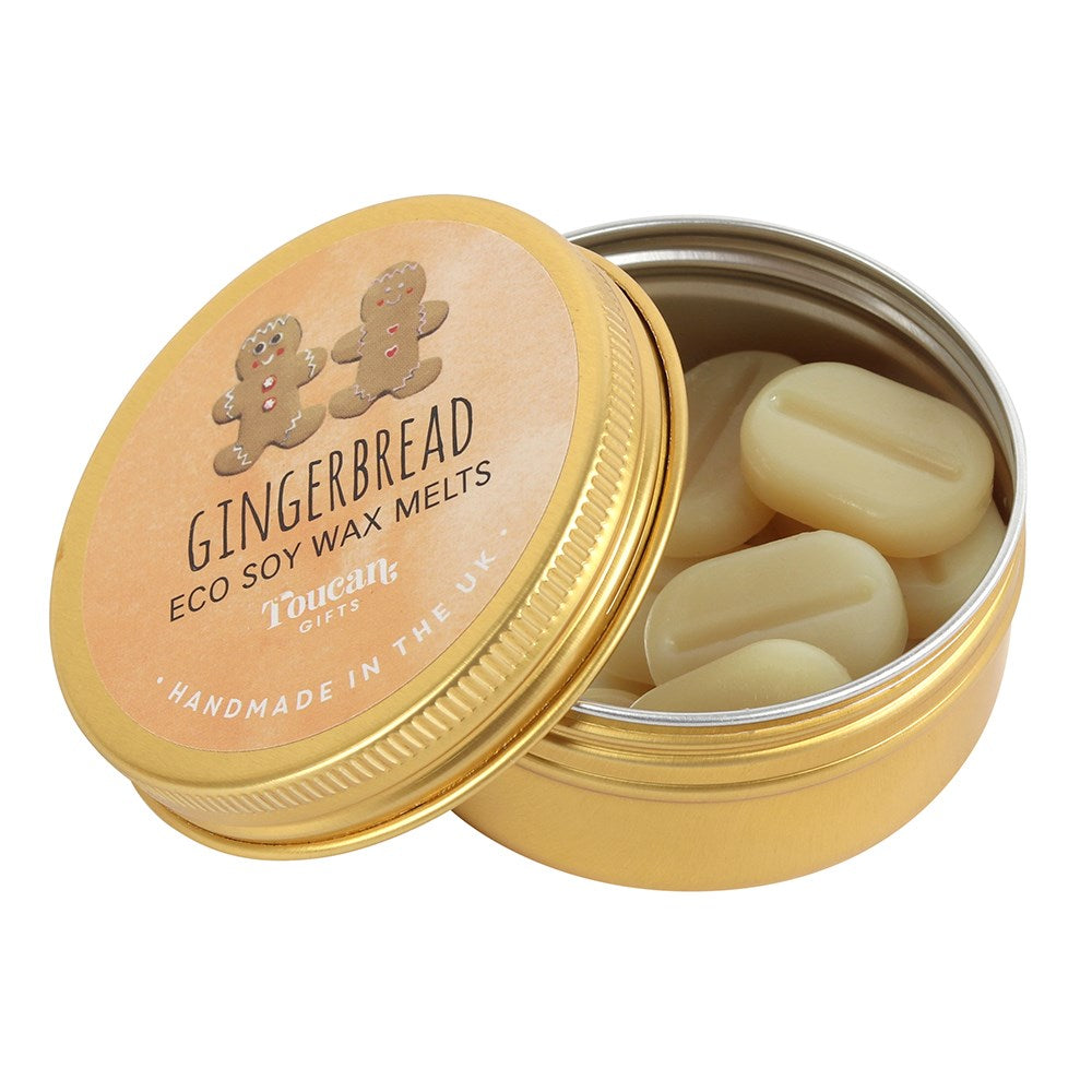 An open golden aluminium tin filled with cream-coloured, coffee-bean-shaped eco soy wax melts, showcasing the circular brown gingerbread man product label leaning against the container on a clean white background.