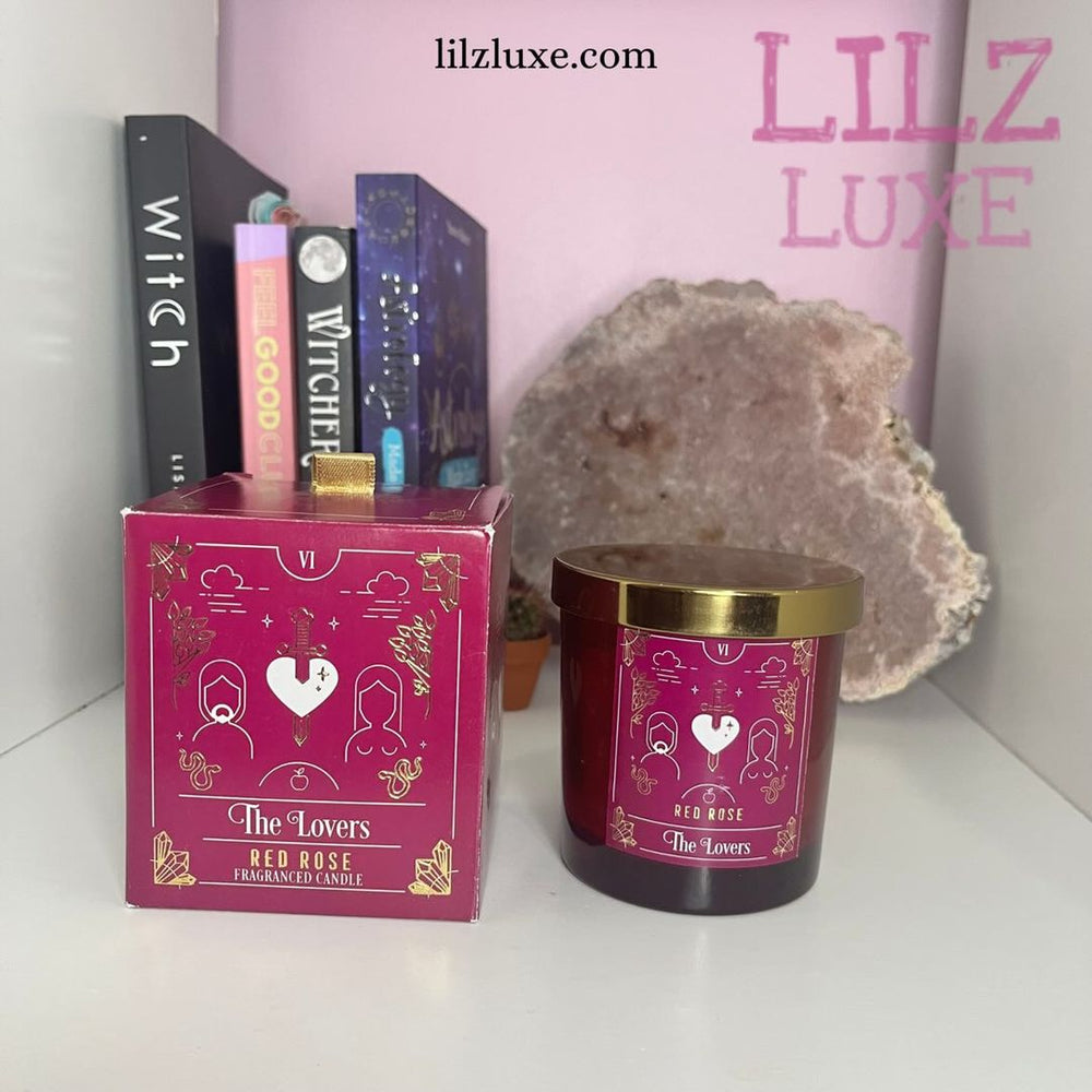 A matching red gift box featuring a line-art heart and sword illustration sitting alongside the imperfect red glass tarot candle jar on an altar shelf, demonstrating the complete packaging design of this clearance item.