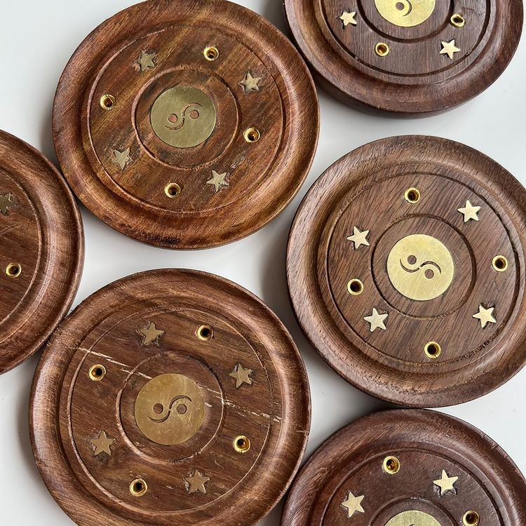 A top-down view of several circular Sheesham wood mini Yin Yang incense stick holders arranged flat against a clean white surface. Each compact wooden ash catcher displays a rich natural grain pattern, beautifully detailed with a central brass-inlaid Yin Yang balance symbol, delicate engraved gold stars, and multiple pre-drilled holes to anchor a grounding everyday meditation routine.