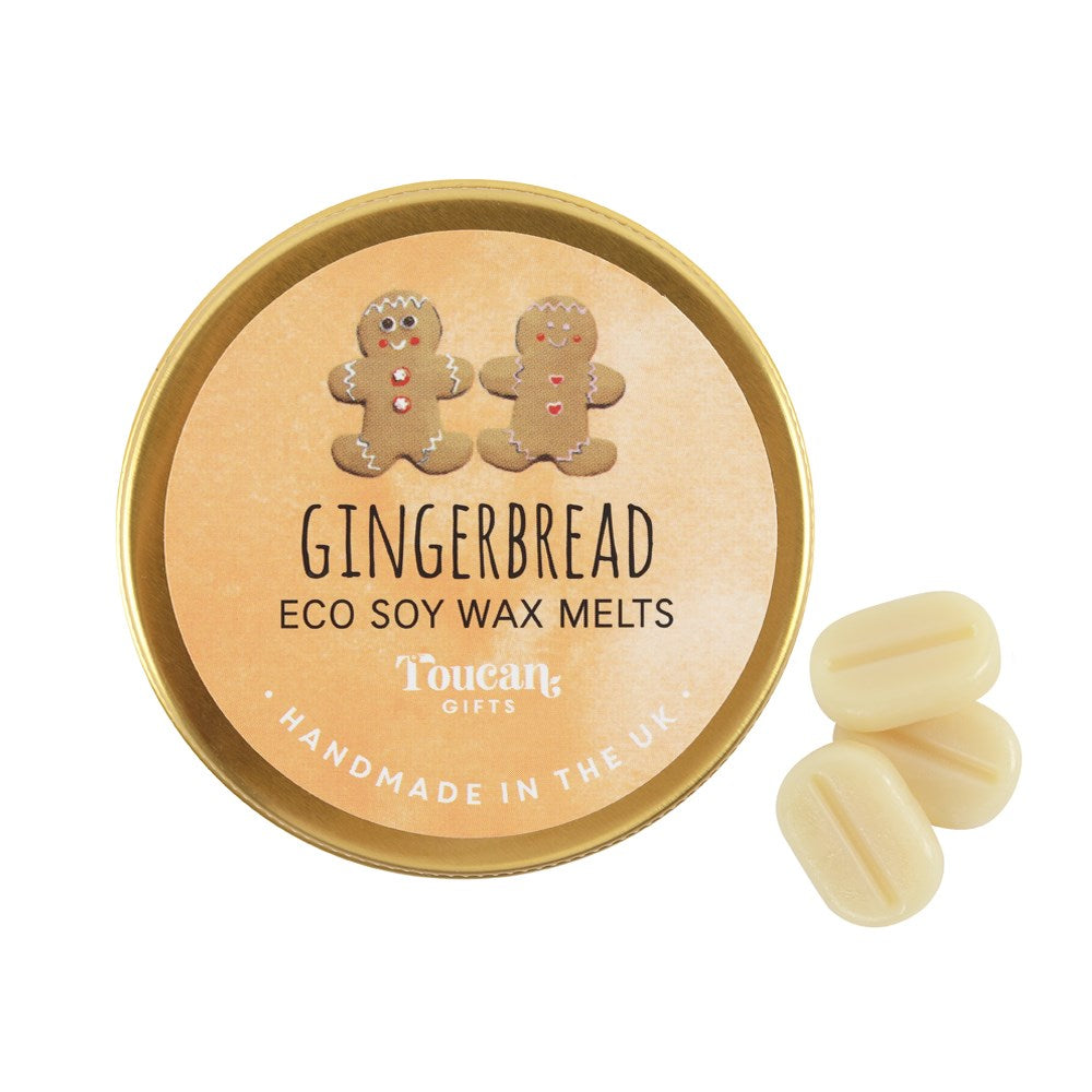 A top-down view of the closed gold circular tin lid for the gingerbread eco soy wax melts next to three loose cream mini melts, highlighting the handcrafted plastic-free home fragrance design.