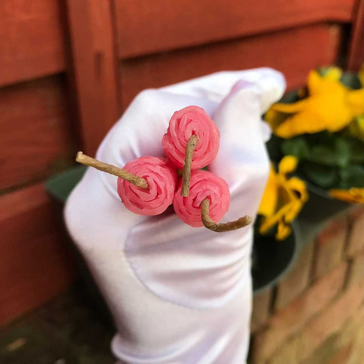 A top-down macro shot looking straight onto three pink beeswax manifestation candles bundled tightly together in a white gloved hand. The unique perspective captures the concentric circular layers of the hand-rolled honeycomb design surrounding the unlit premium natural linen wicks.
