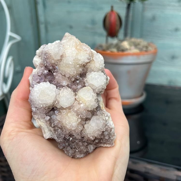 A close-up shot of a rugged lilac spirit quartz crystal cluster cradled in an open palm, showing hundreds of tiny shimmering points #style_c