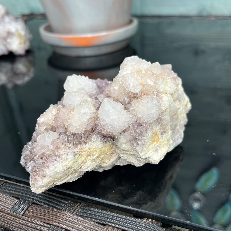 A hand presenting a spiky purple spirit quartz cluster crystal to highlight its unique druzy texture and pale amethyst shading.  #style_c