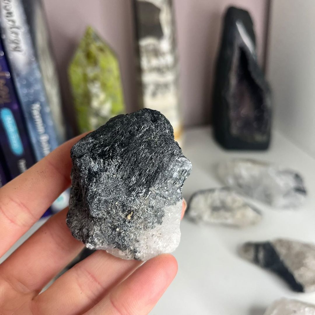 A hand cradling an unpolished tourmaline quartz healing crystal specimen, revealing its dense, dual-mineral texture that gracefully balances higher spiritual growth with deep physical stability.